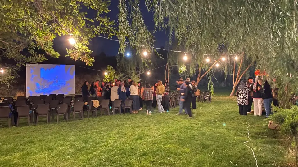Ağaçlar altında ışık telleriyle aydınlanan açık hava sineması perdesi, Konya