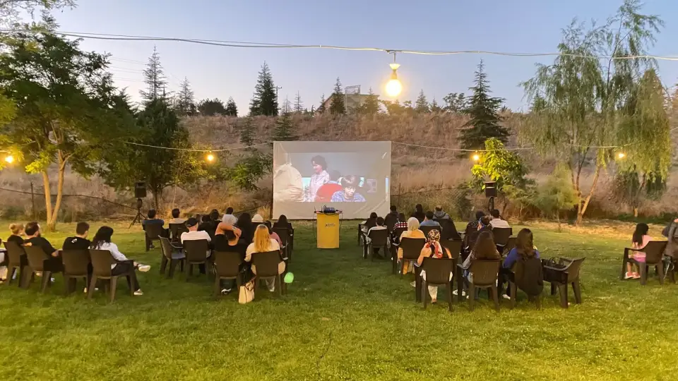 Akşam gökyüzü altında çimli alanda film izleyen kalabalık, Konya
