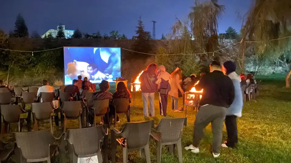 Ateş yanında sohbet eden izleyiciler ve sandalyeler, açık hava sineması Konya