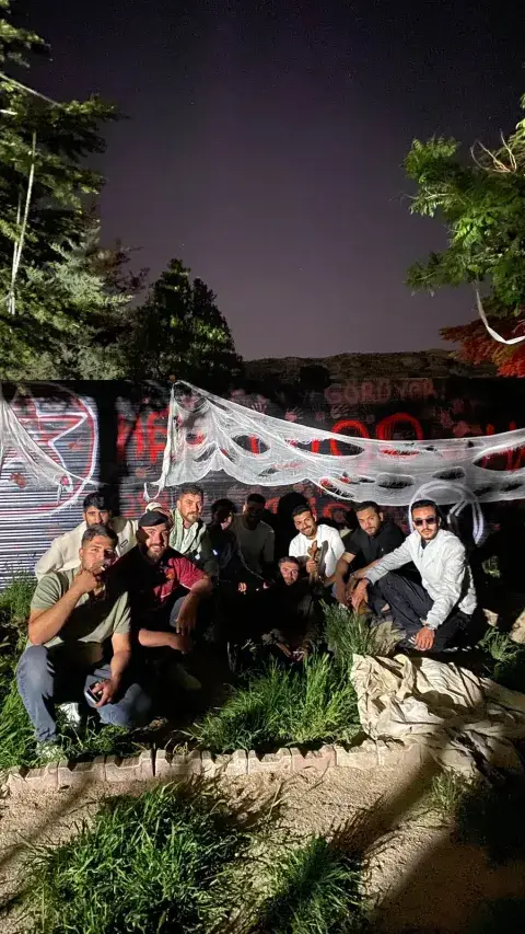 Örümcek ağlı duvar önünde toprağa oturmuş grup, korku köyü Konya