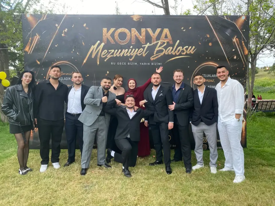 Açık havada mezuniyet balosu fonu önünde siyah takımlı grup, Konya