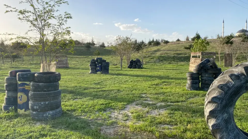 Gün batımında ağaçlar ve siperlerle paintball alanı, Konya