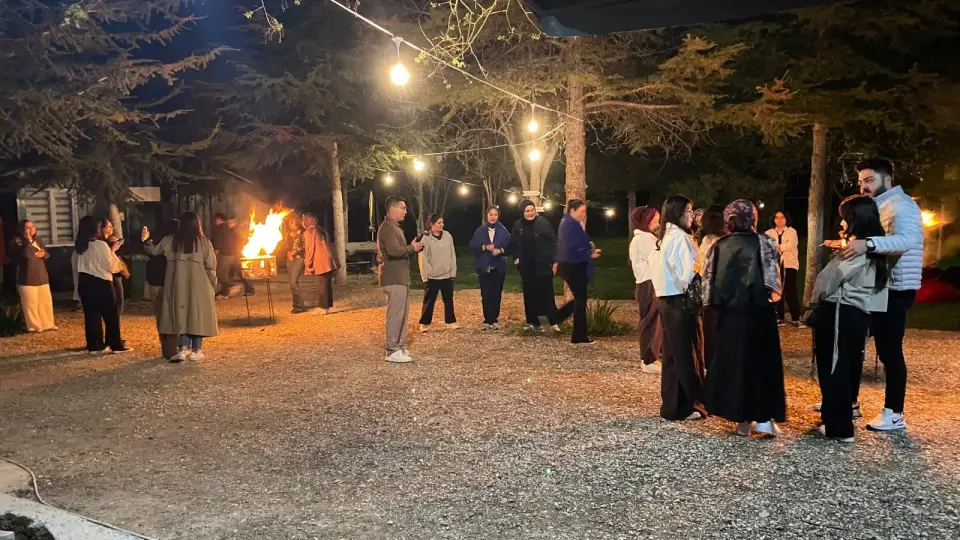 Gece ışıkların altında ateş yanında toplanan katılımcılar, Konya